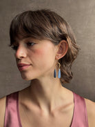 Woman wearing Delta Earrings from New York fine jewelry artist Emilie Shapiro with dangling teardrop shaped polished kyanite and warm textured half circle brass dangle gracefully from handmade gold filled earring wires