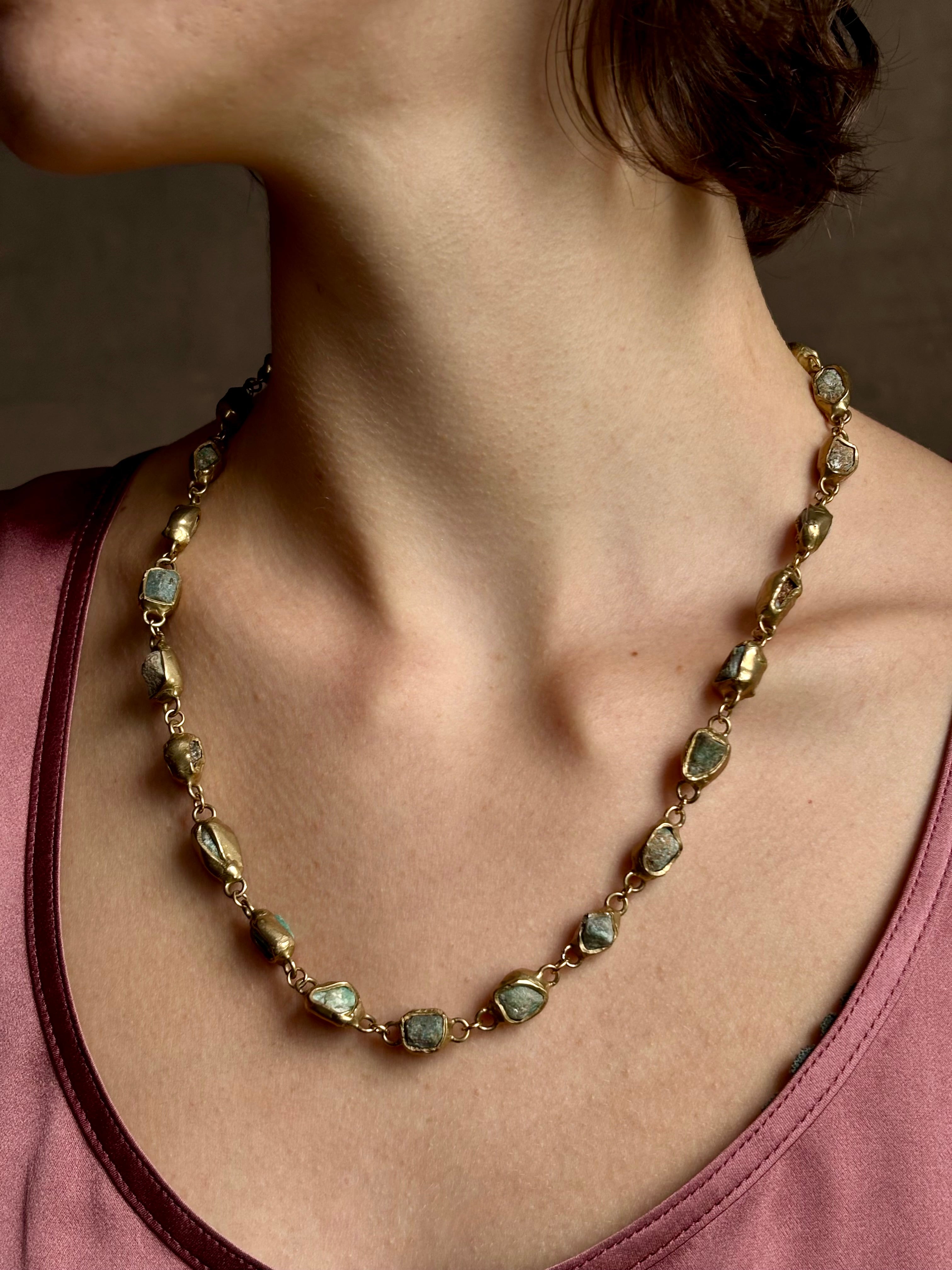 Woman wearing Guardian Path Necklace from jewelry designer Emilie Shapiro with posts on Natural emeralds individually embedded in warm brass along a clean, linear path for a beautiful statement piece handcrafted in USA