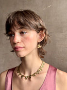Woman wearing Hydrangea Earrings from New York fine jewelry artist Emilie Shapiro are botanically inspired with Raw sapphires embedded in warm, textured brass dangle from gold wire hoops handcrafted in USA