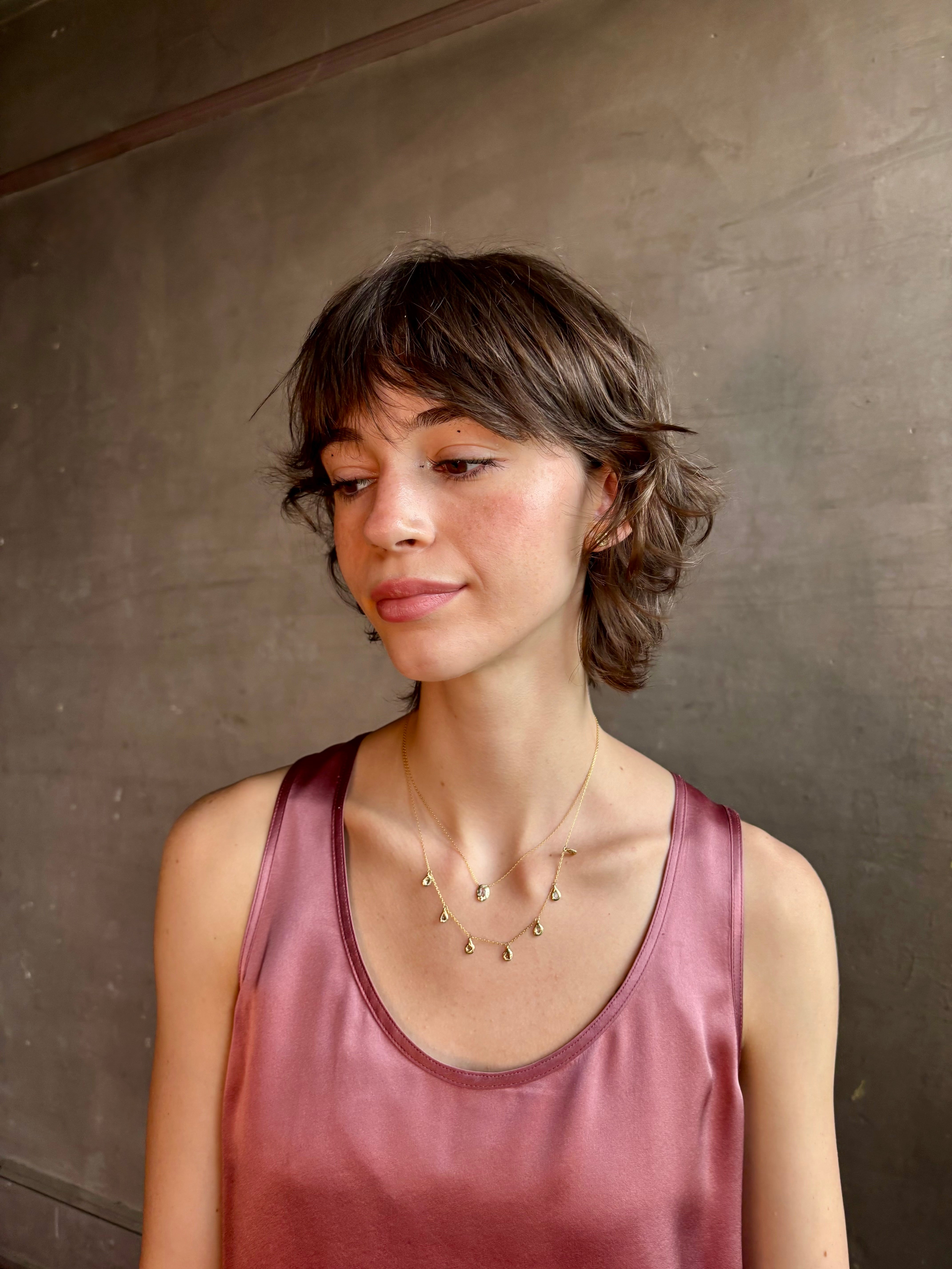 Woman wearing Mirage Cascade Diamond Necklace from New York fine jewelry designer Emilie Shapiro featuring seven dangling rose cut diamonds in 14k yellow gold exquisitely handcrafted in USA