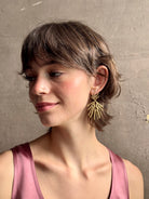 Woman wearing Solaris post Earrings from New York fine jewelry artist Emilie Shapiro that channels the radiant, life-giving energy of the sun in an exquisitely handcrafted textured brass form. Large, statement-making and thoroughly wearable dangle earrings