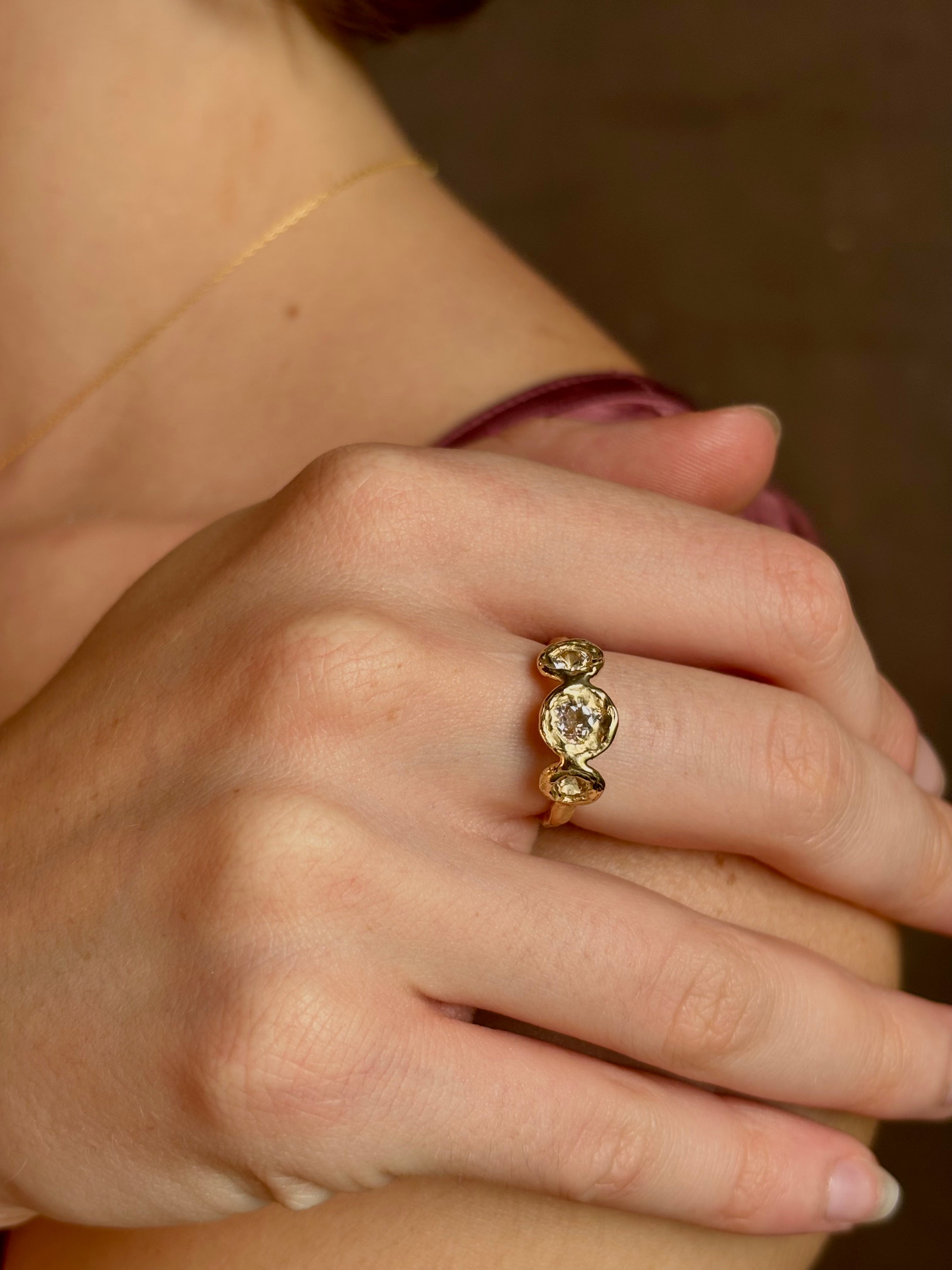 Woman wearing a White Sapphire statement Ring from contemporary fine jewelry designer Emilie Shapiro composed of three round white sapphires set in 14k yellow gold handcrafted in USA