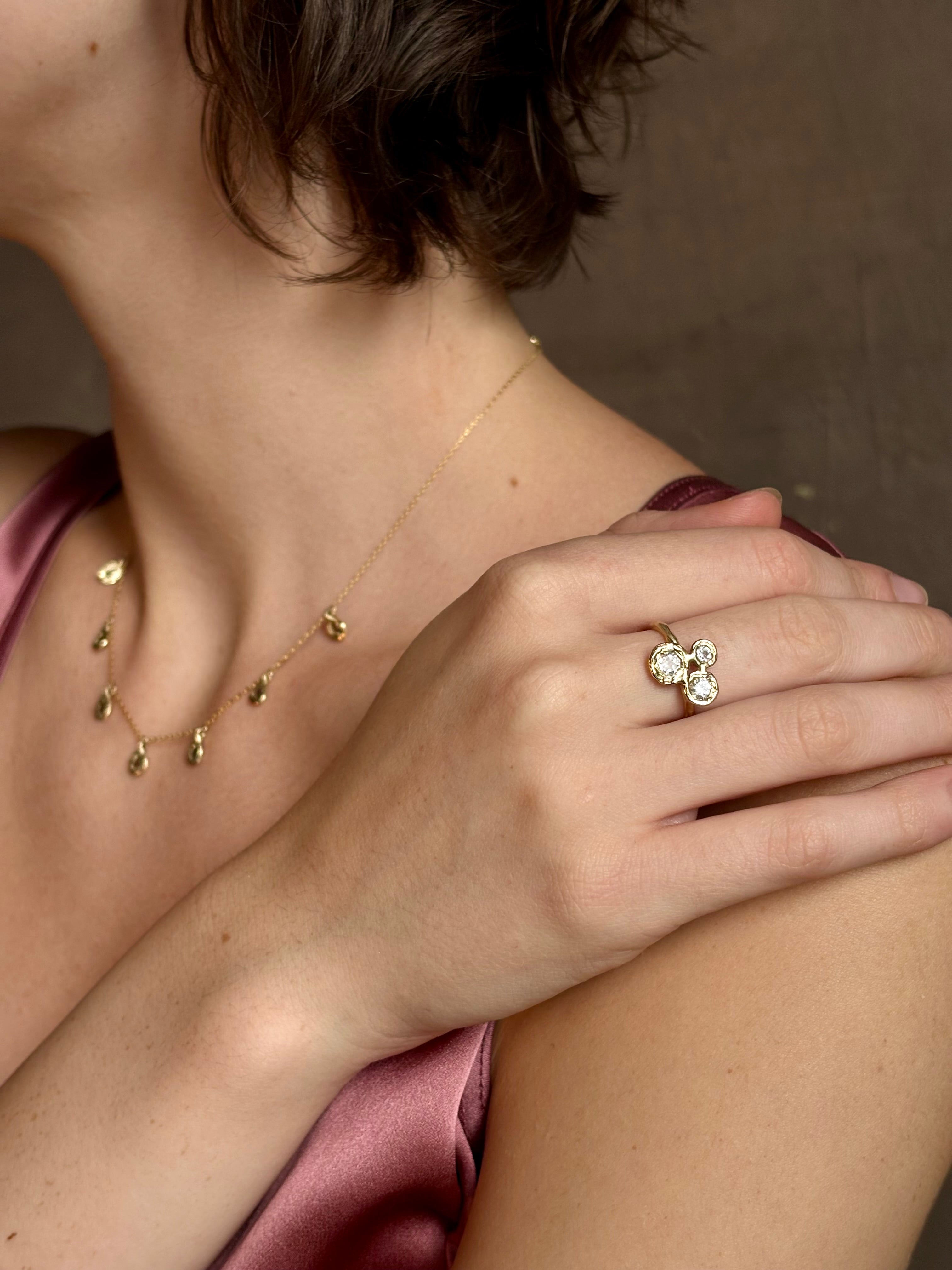 Woman wearing a White Sapphire statement Ring from contemporary fine jewelry designer Emilie Shapiro composed of three round white sapphires set in 14k yellow gold handcrafted in USA