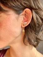 Woman wearing white Sapphire drop earrings from contemporary fine jewelry designer Emilie Shapiro composed of a single round white sapphires set in 14k yellow gold handcrafted in USA