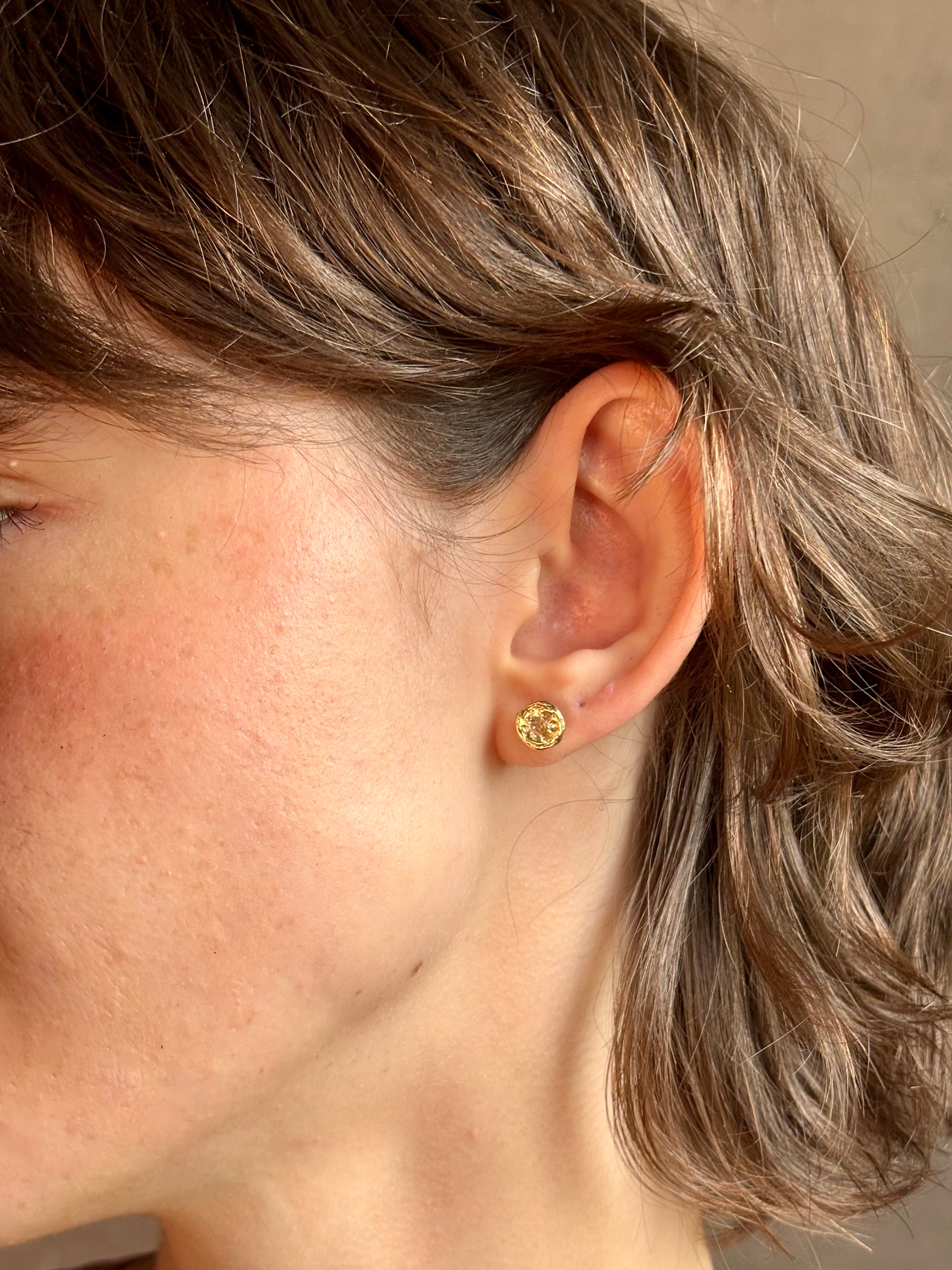 Woman wearing white Sapphire stud earrings from contemporary fine jewelry designer Emilie Shapiro composed of a single round white sapphires set in 14k yellow gold handcrafted in USA