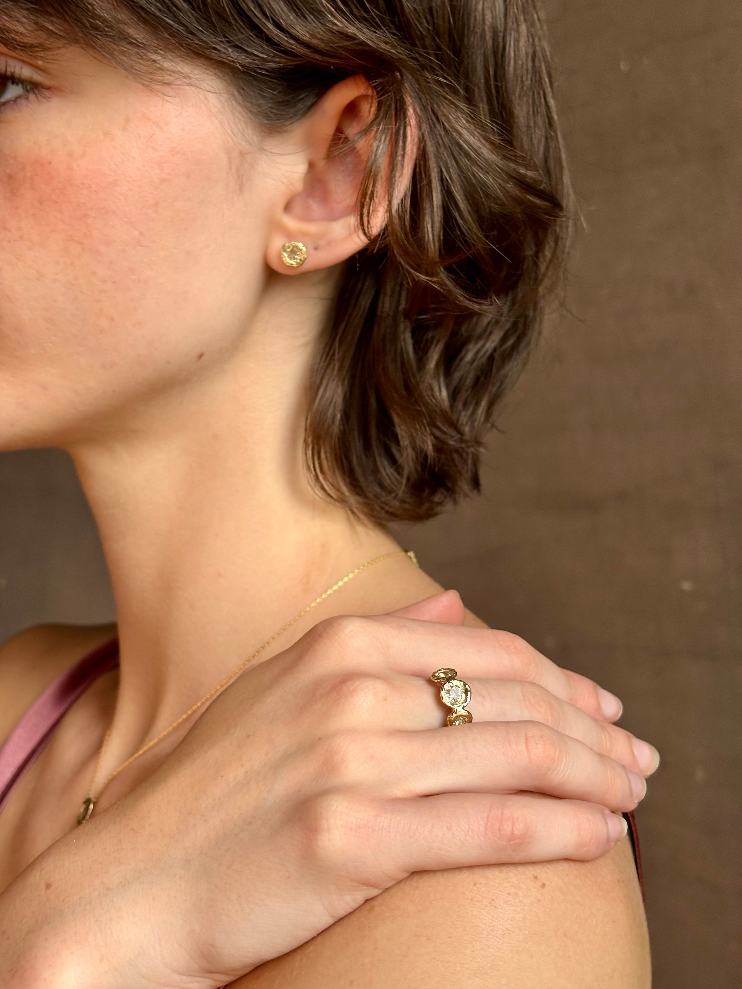 Woman wearing white Sapphire stud earrings from contemporary fine jewelry designer Emilie Shapiro composed of a single round white sapphires set in 14k yellow gold handcrafted in USA