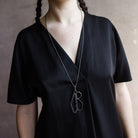 Woman wearing a black top and showcasing a sterling silver and spinel pendant necklace with a geometric design by North Carolina jewelry artist Erica Bailey
