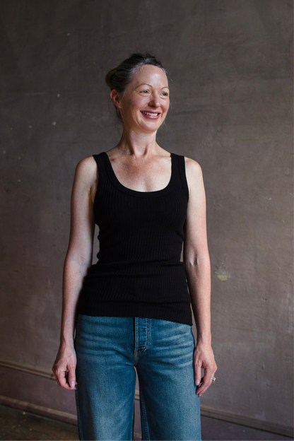 Image featuring a woman wearing the organic cotton tank top by Enza Costa is crafted from sweater rib material with a feminine U-neckline and a tubular finish in black.