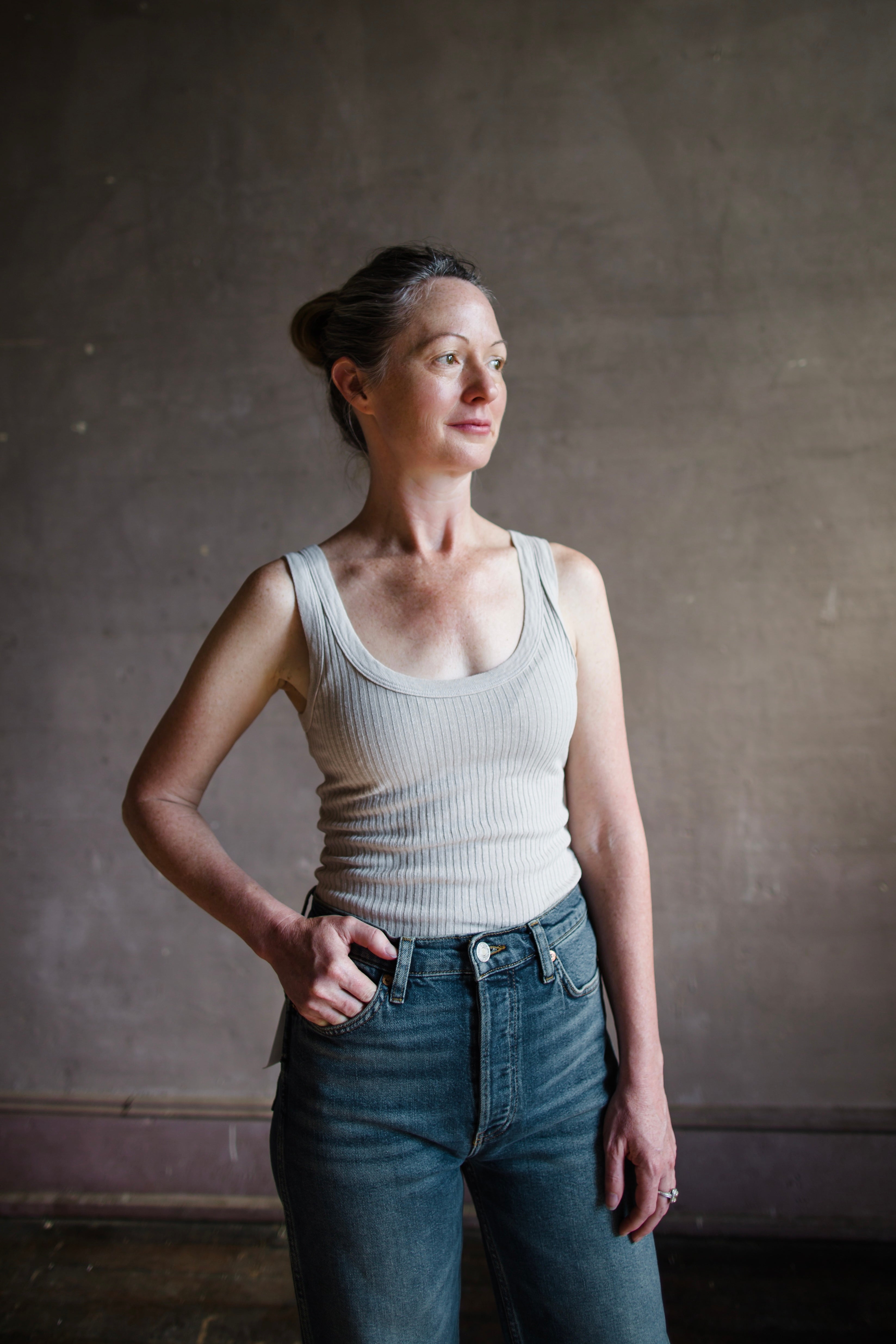 Image featuring a woman wearing the organic cotton tank top by Enza Costa is crafted from sweater rib material with a feminine U-neckline and a tubular finish in flax.