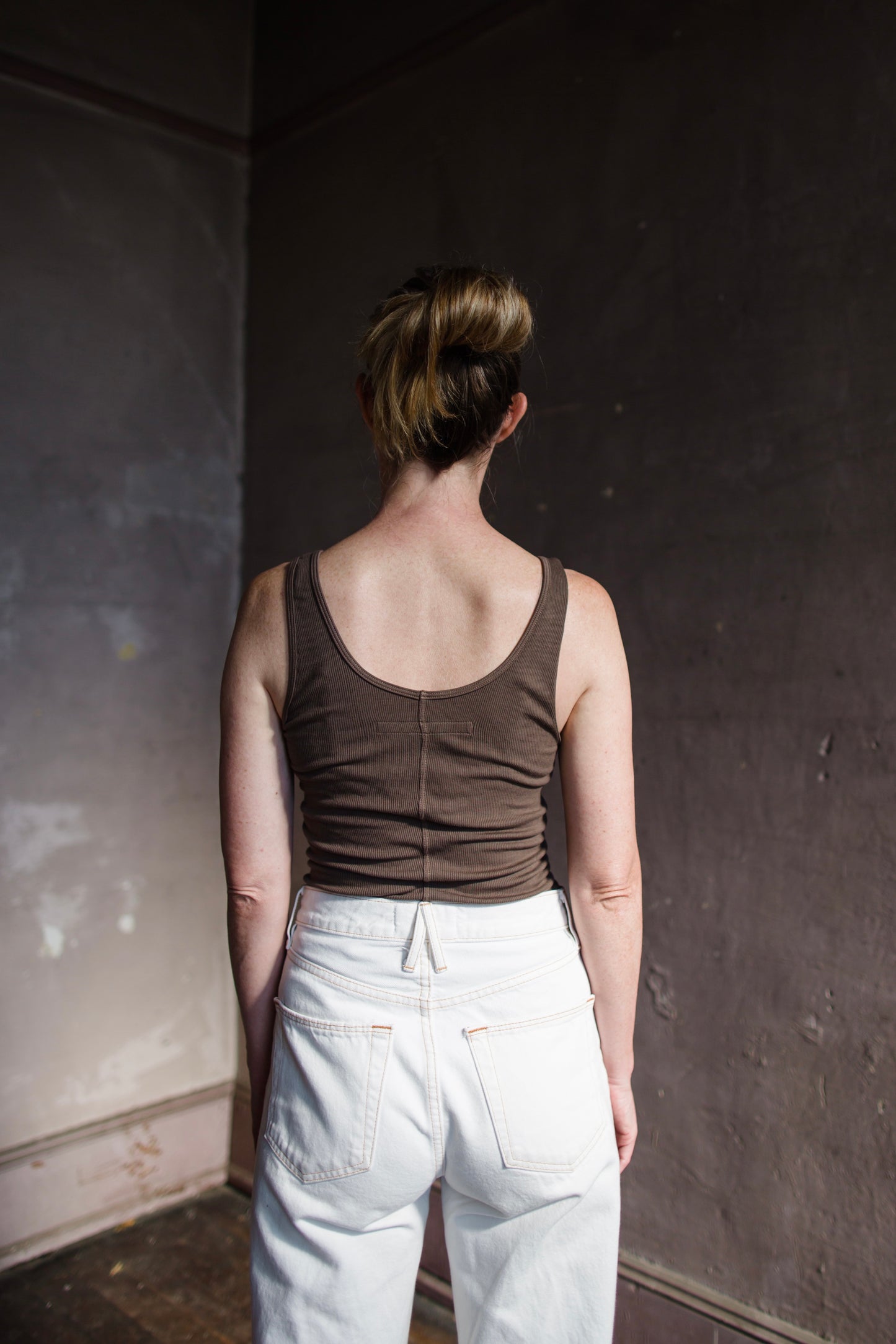 Image featuring a woman wearing the tank top from Enza Costa crafted with soft rib fabric and offers a body-skimming fit with flattering stretch in mushroom brown.