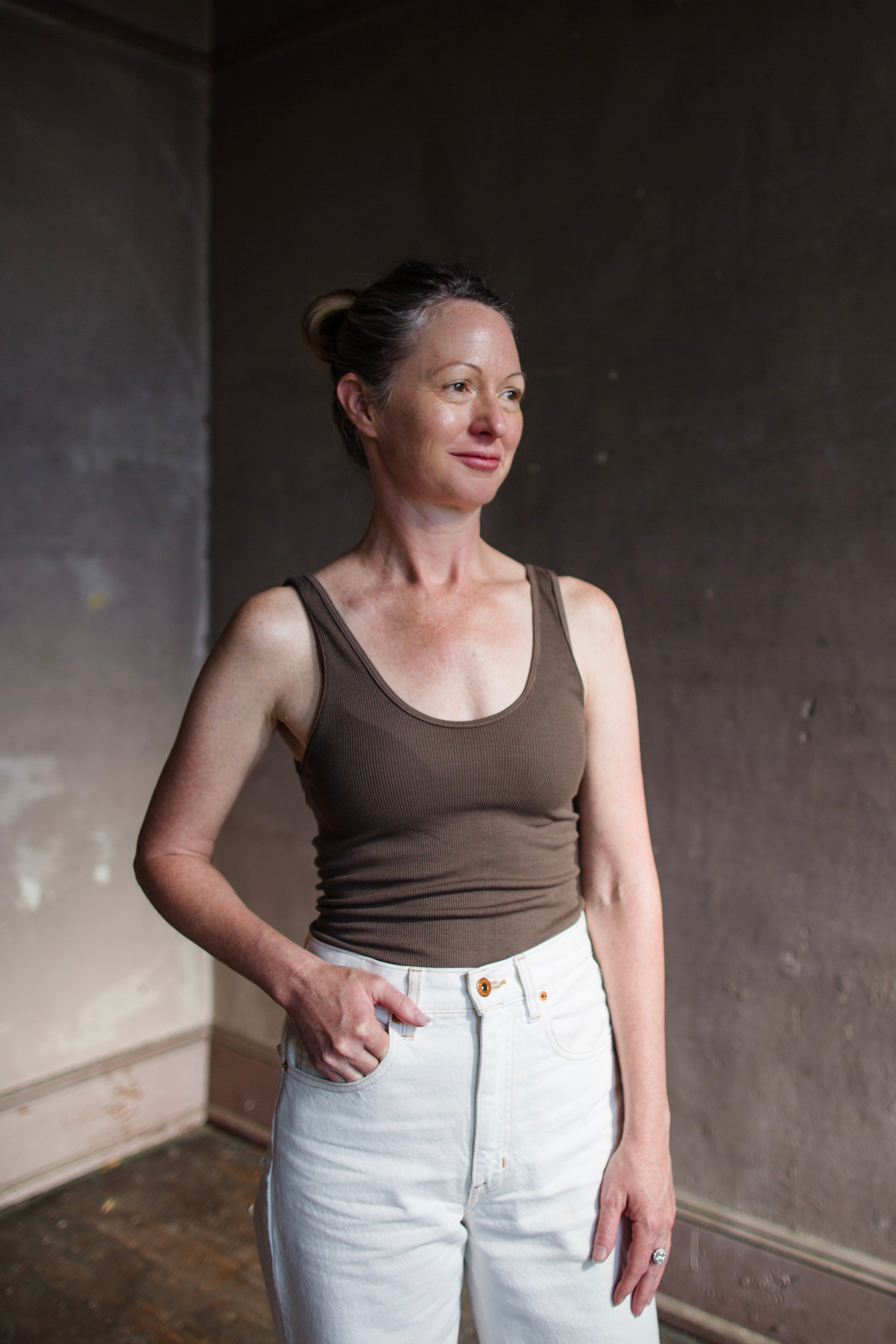 Image featuring a woman wearing the tank top from Enza Costa crafted with soft rib fabric and offers a body-skimming fit with flattering stretch in mushroom brown.