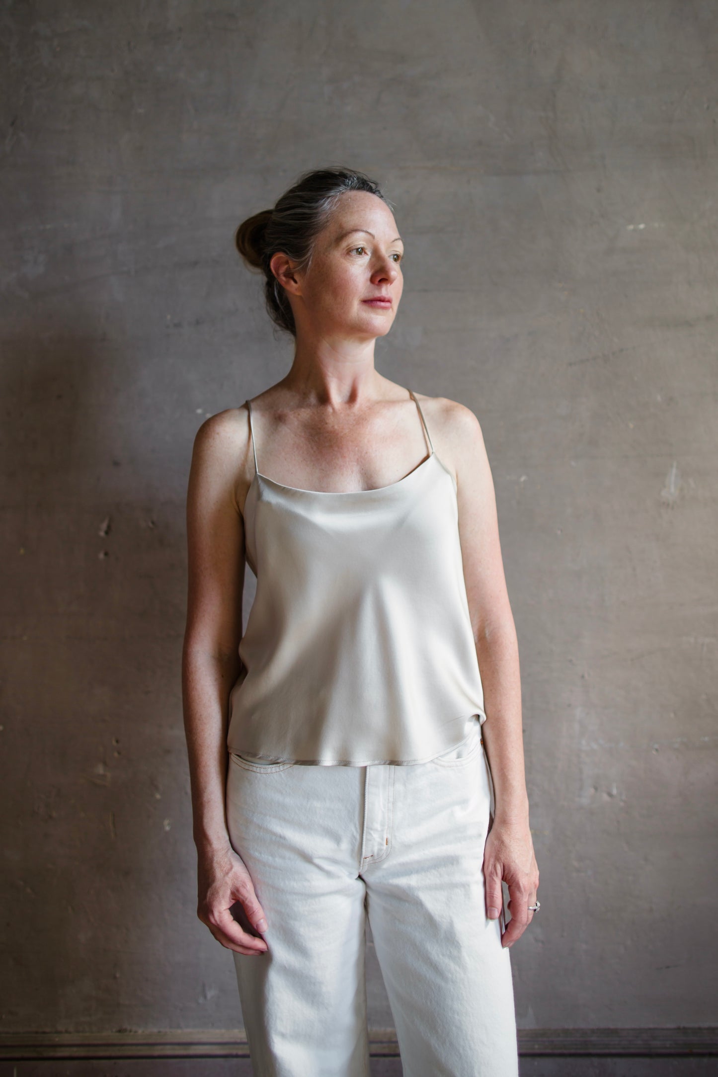 Image featuring a woman wearing the taupe Silk Satin Camisole from Enza Costa with a feminine scoop neckline, delicate straps, a gently flared hem and relaxed fit.