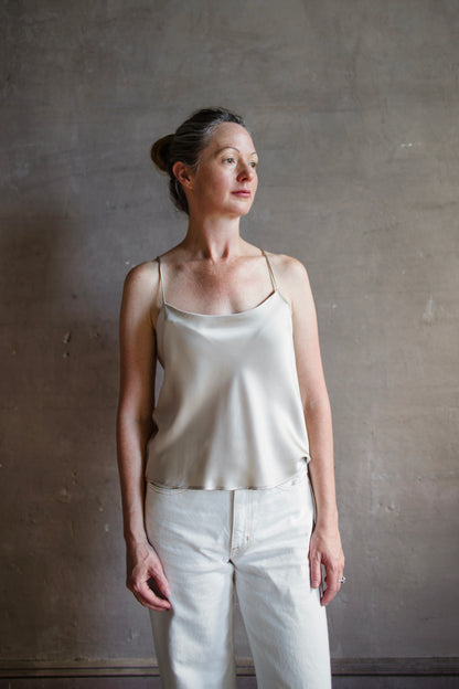 Image featuring a woman wearing the taupe Silk Satin Camisole from Enza Costa with a feminine scoop neckline, delicate straps, a gently flared hem and relaxed fit.