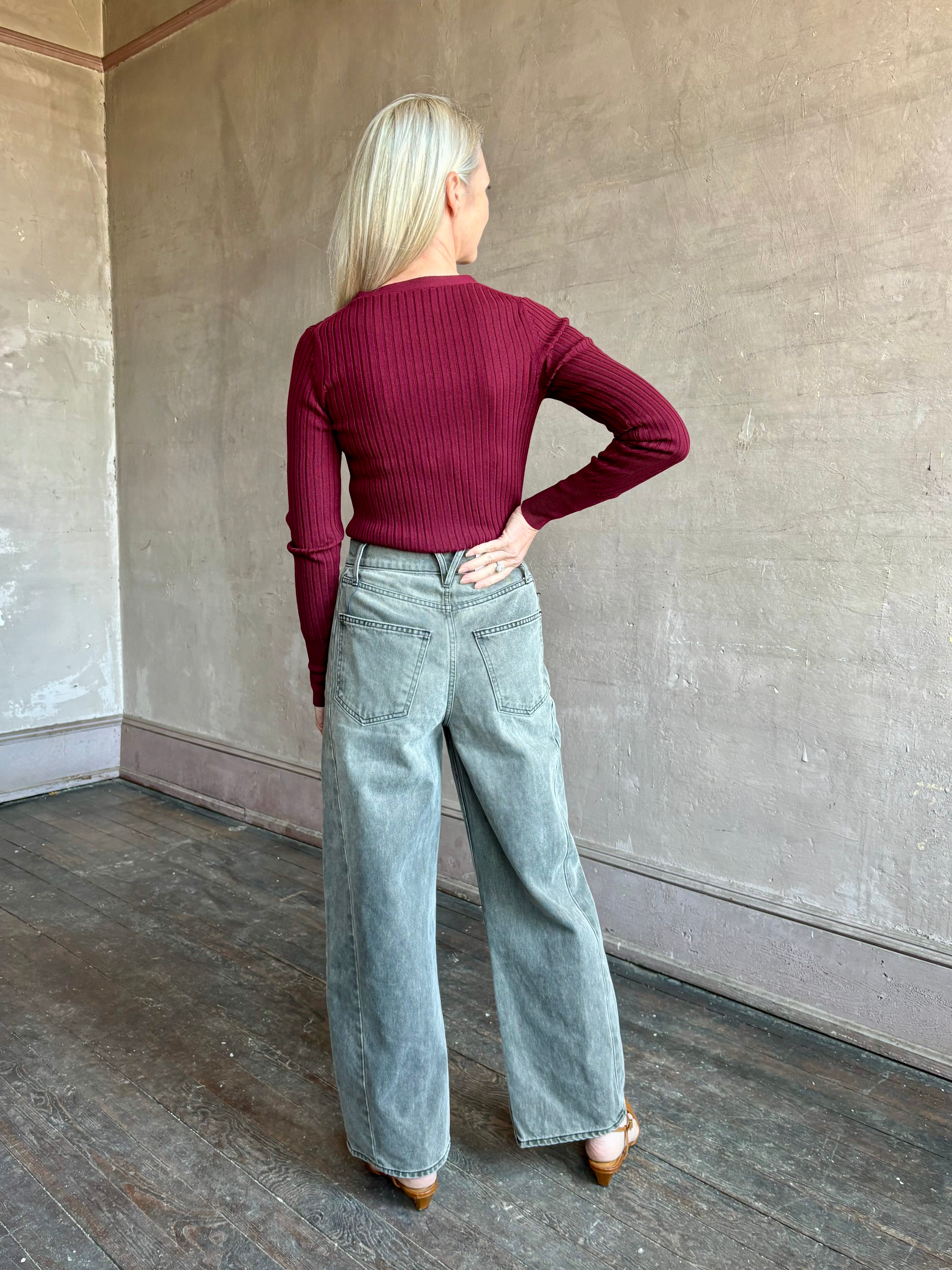 Image of woman wearing premium virgin wool cardigan with v-neck, ribbed texture and long sleeves in a rich burgundy 