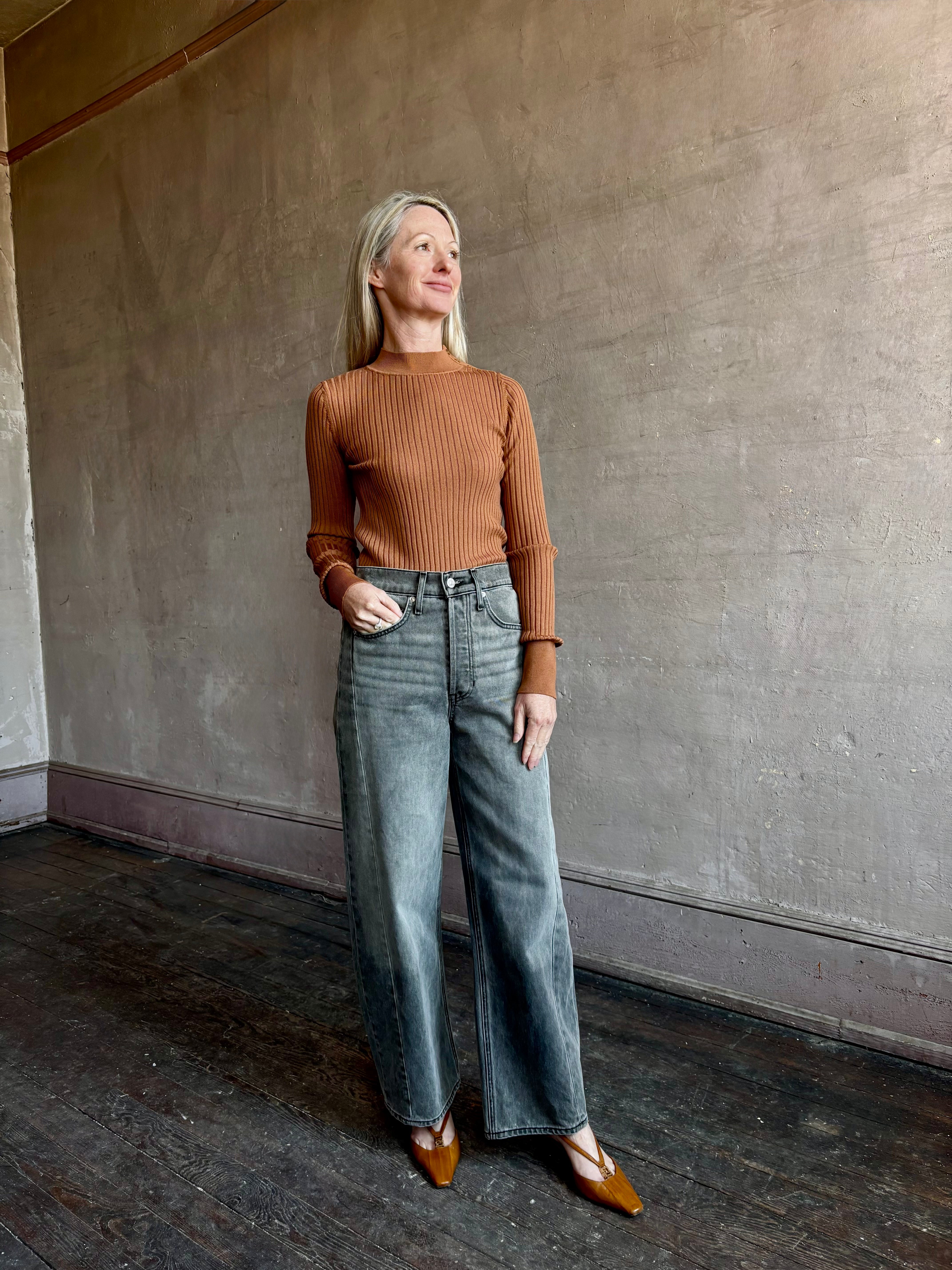 Image of woman wearing luxury Italian Forte Forte Superfine Merino Ribbed Turtleneck Sweater in neutral carmel colorway with long sleeves