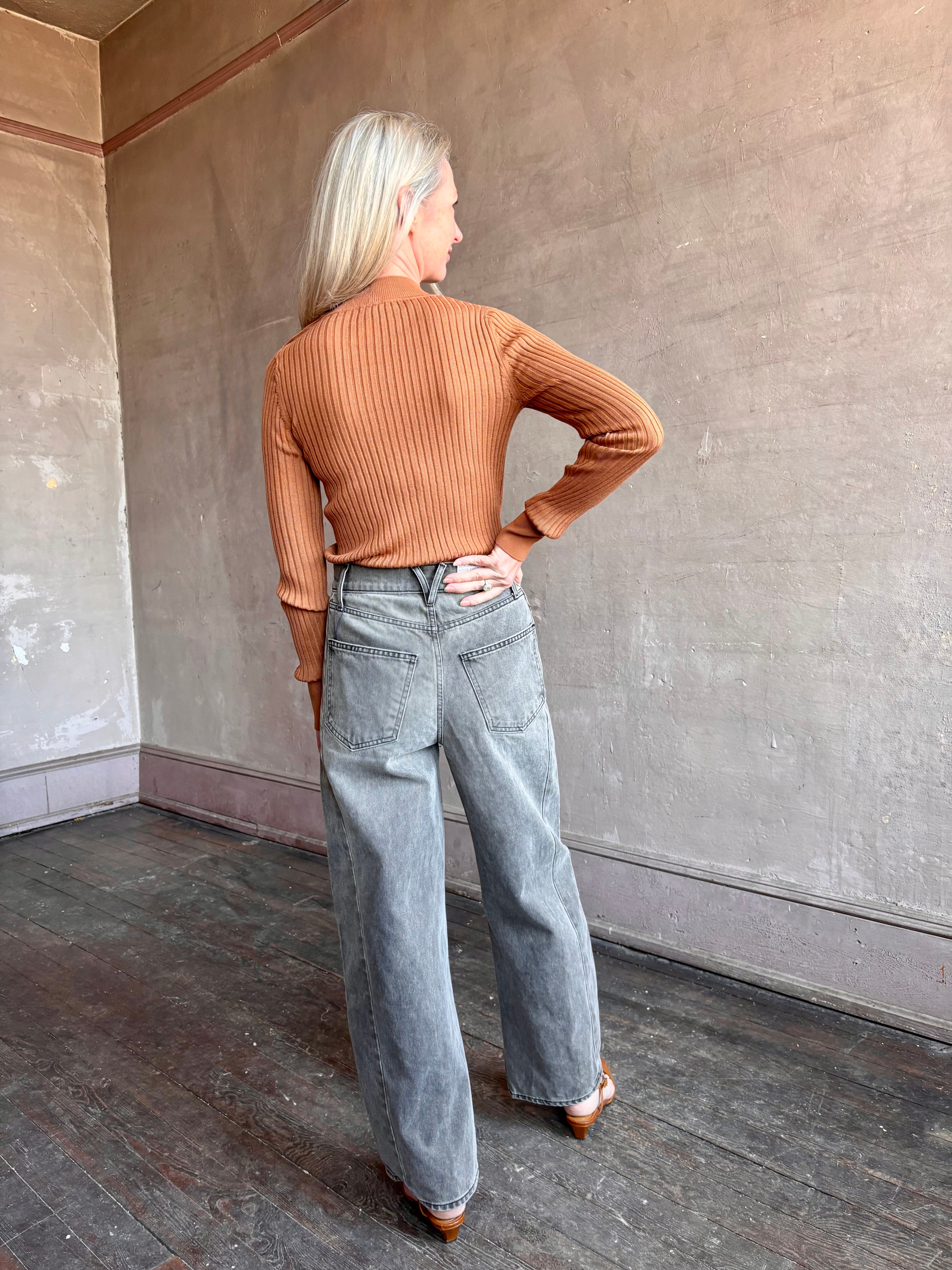 Image of woman wearing luxury Italian Forte Forte Superfine Merino Ribbed Turtleneck Sweater in neutral carmel colorway with long sleeves