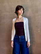 Woman wearing timeless luxury Italian knitwear by FORTE FORTE Superfine Merino Ribbed Cardigan in Neve off-white with v-neck, button front and long sleeves