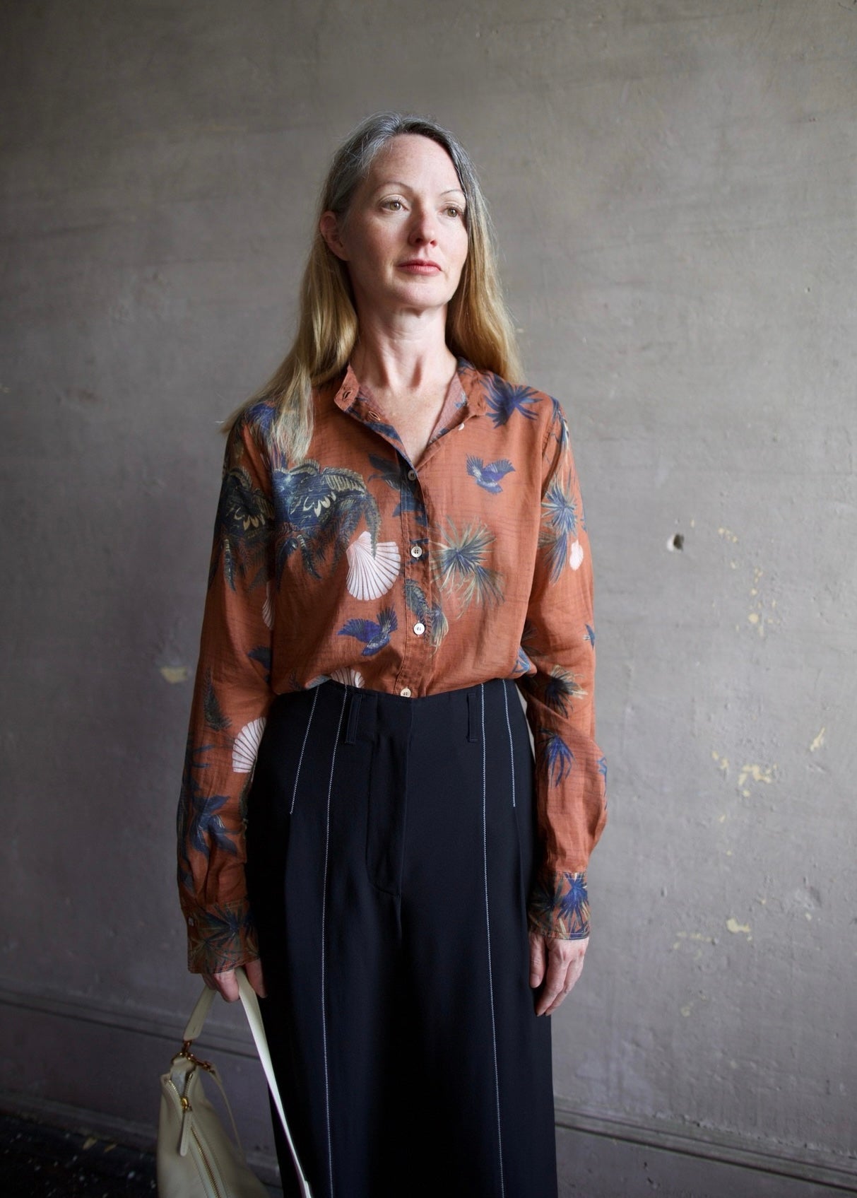 Image featuring a woman wearing the Coreana voile shirt by Forte Forte in a lightweight cotton silk rust color body and a teal fauna print with pink sea scallop shells.