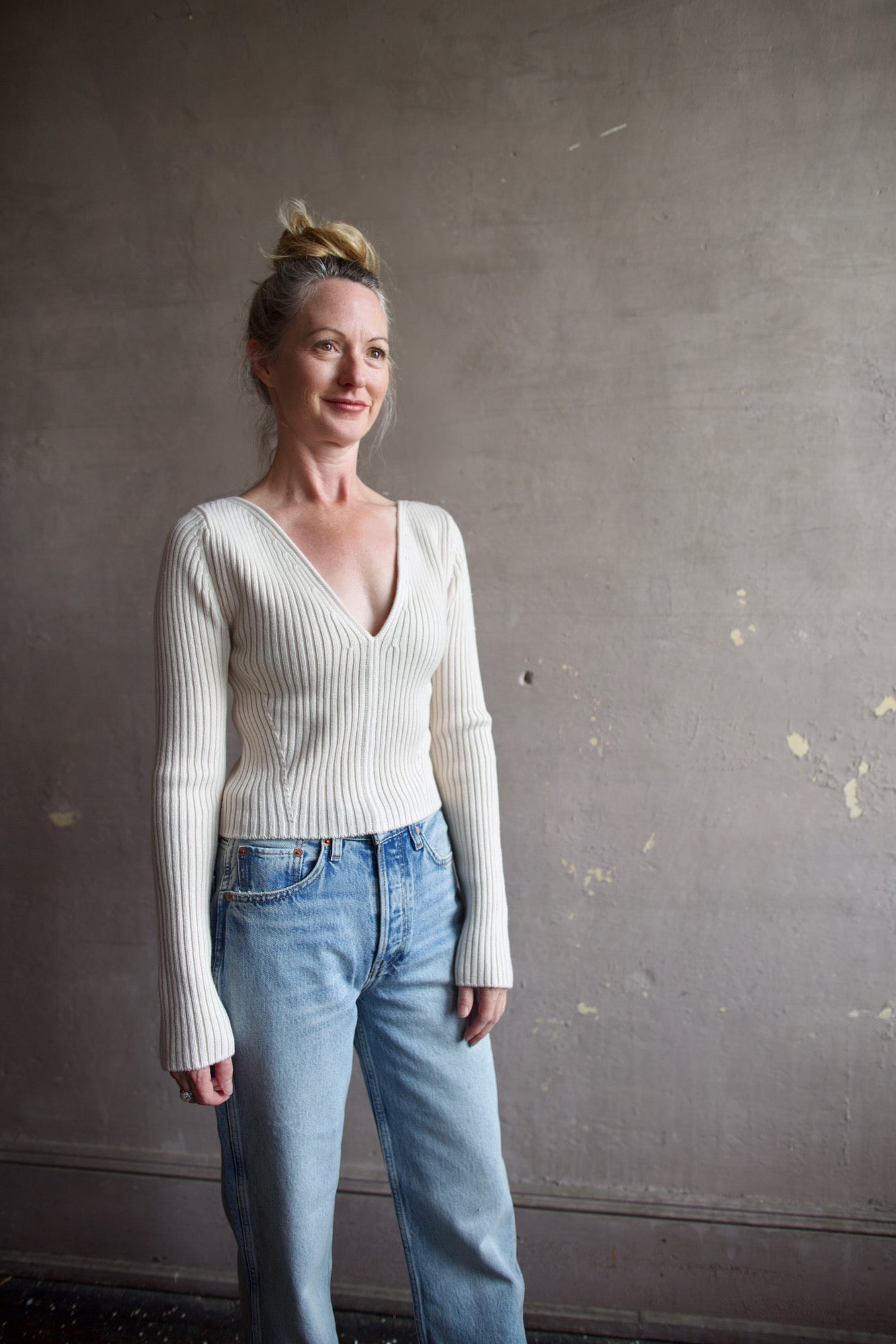 Image featuring a woman wearing the Forte Forte Deep Neckline Ribbed Stretch Merino Sweater with a v-neckline and a cropped fit.