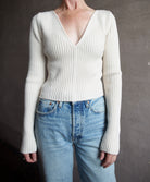 Image featuring a woman wearing the Forte Forte Deep Neckline Ribbed Stretch Merino Sweater with a v-neckline and a cropped fit.