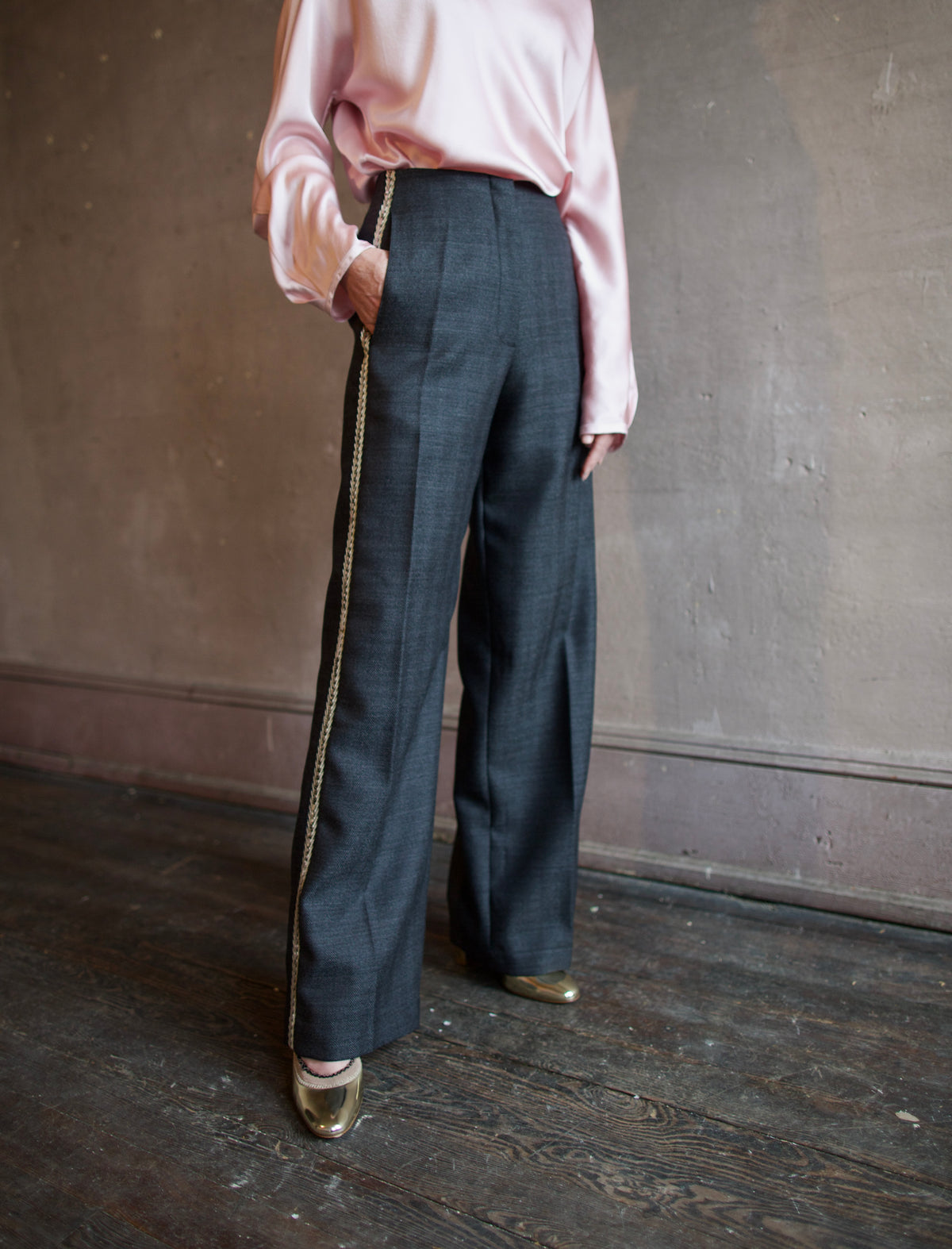 Mature woman wearing Forte_Forte's tailored Grey Herringbone Pants in virgin wool asymmetrical sequence embellishment down side