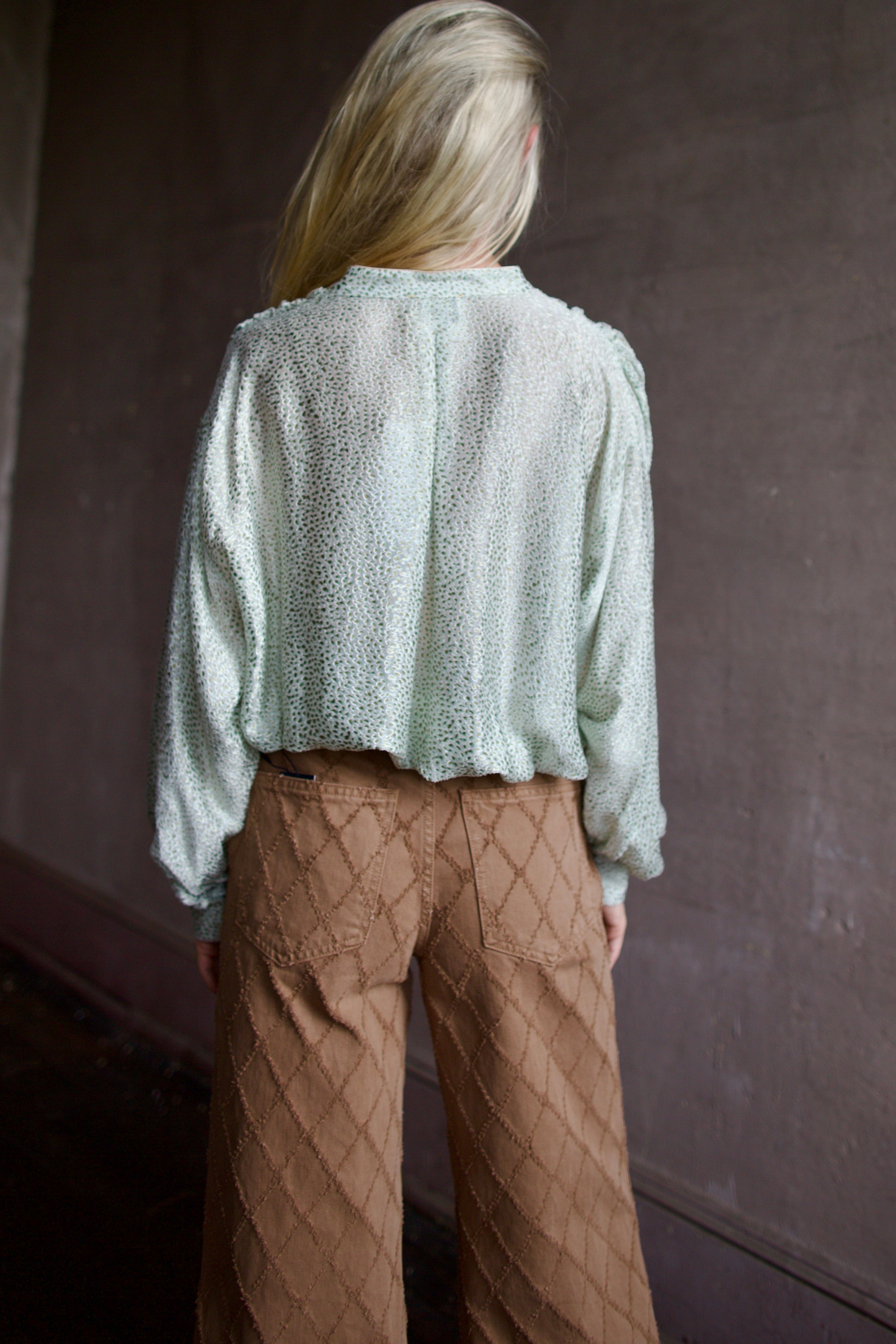 Back of mature model wearing a light weight white and mint green blouse from high-end fashion designer Forte Forte 