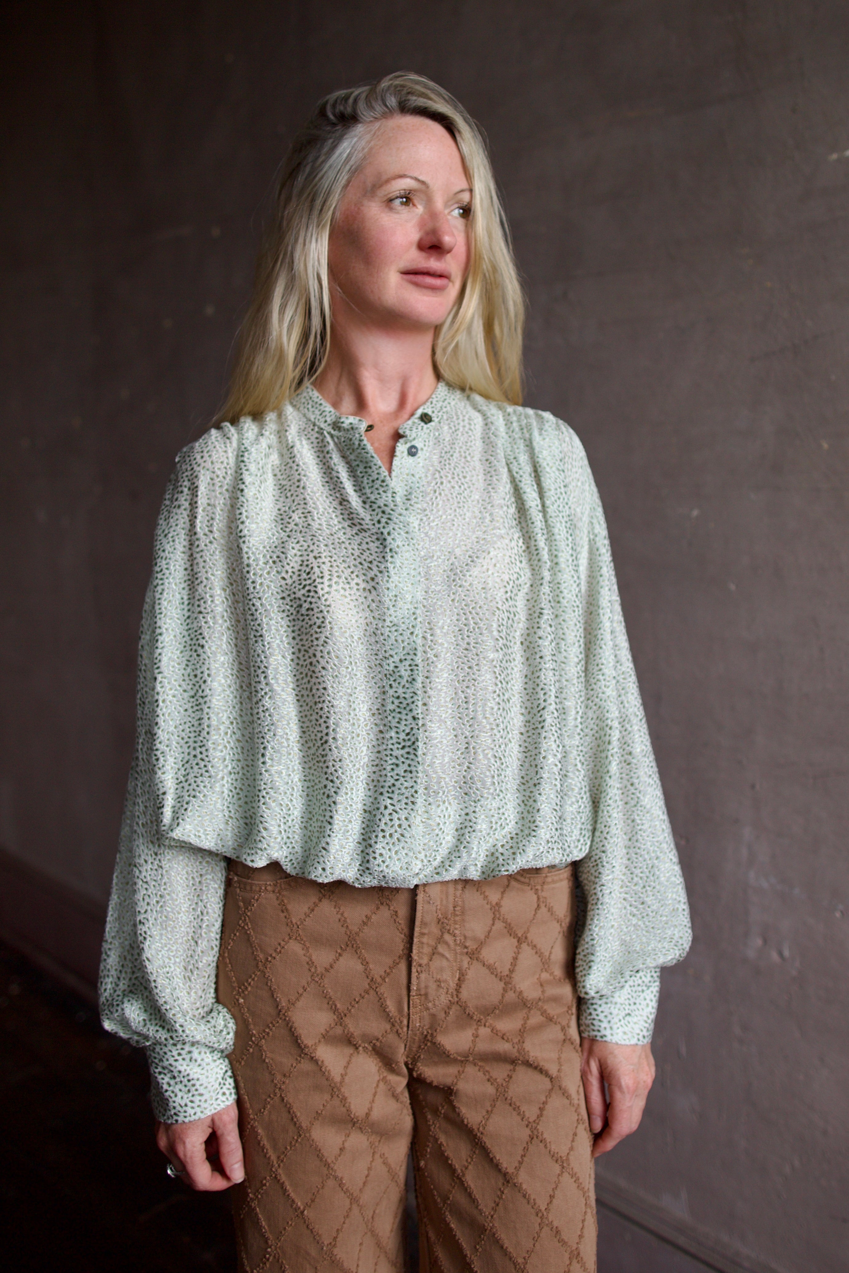 Mature model wearing a light weight white and mint green blouse from high-end fashion designer Forte Forte