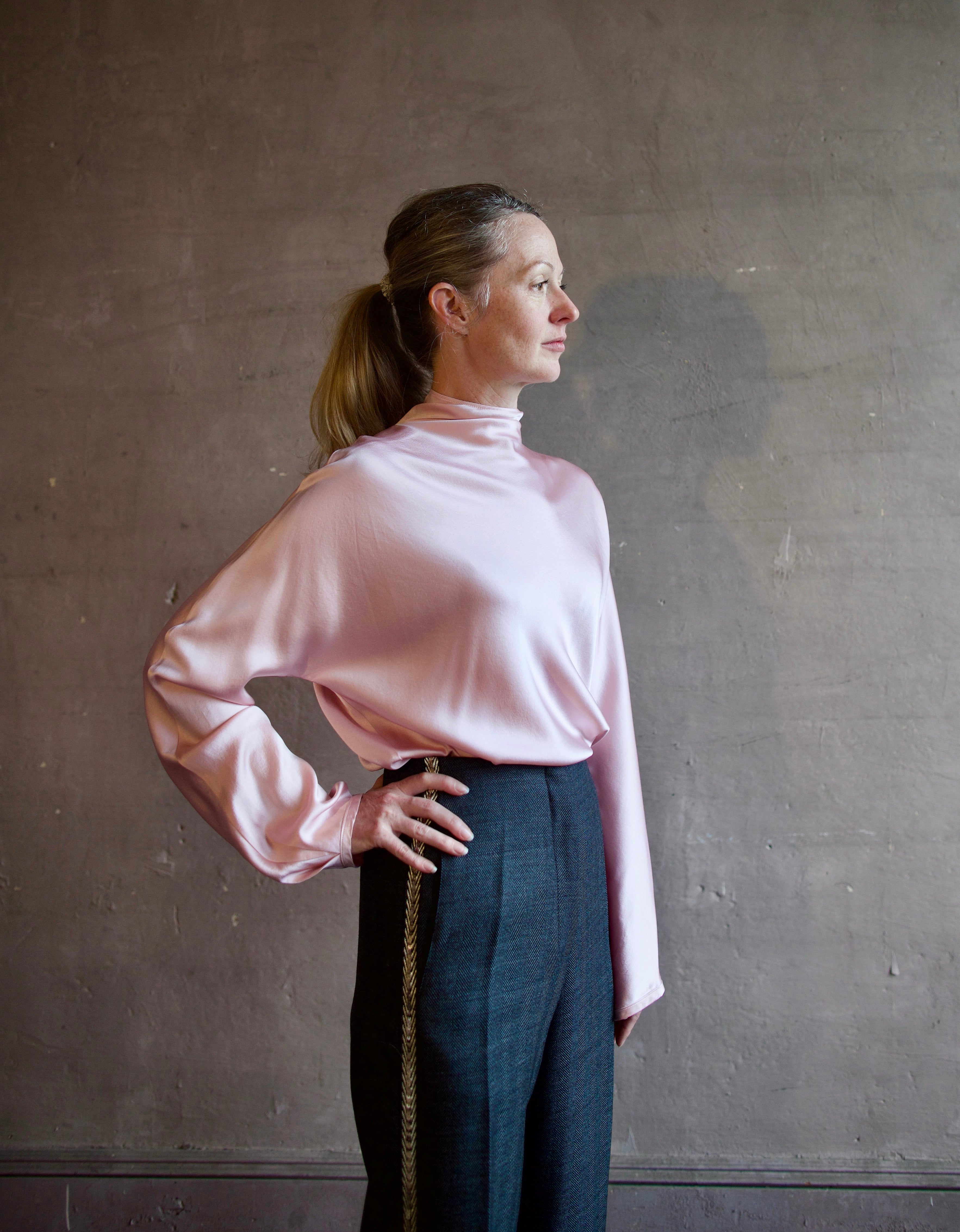 Image featuring a woman wearing the satin crater neck silk shirt by Forte Forte with s a high neckline, zip closure and a relaxed fit in a light pink color.