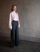 Image featuring a woman wearing the satin crater neck silk shirt by Forte Forte with s a high neckline, zip closure and a relaxed fit in a light pink color.