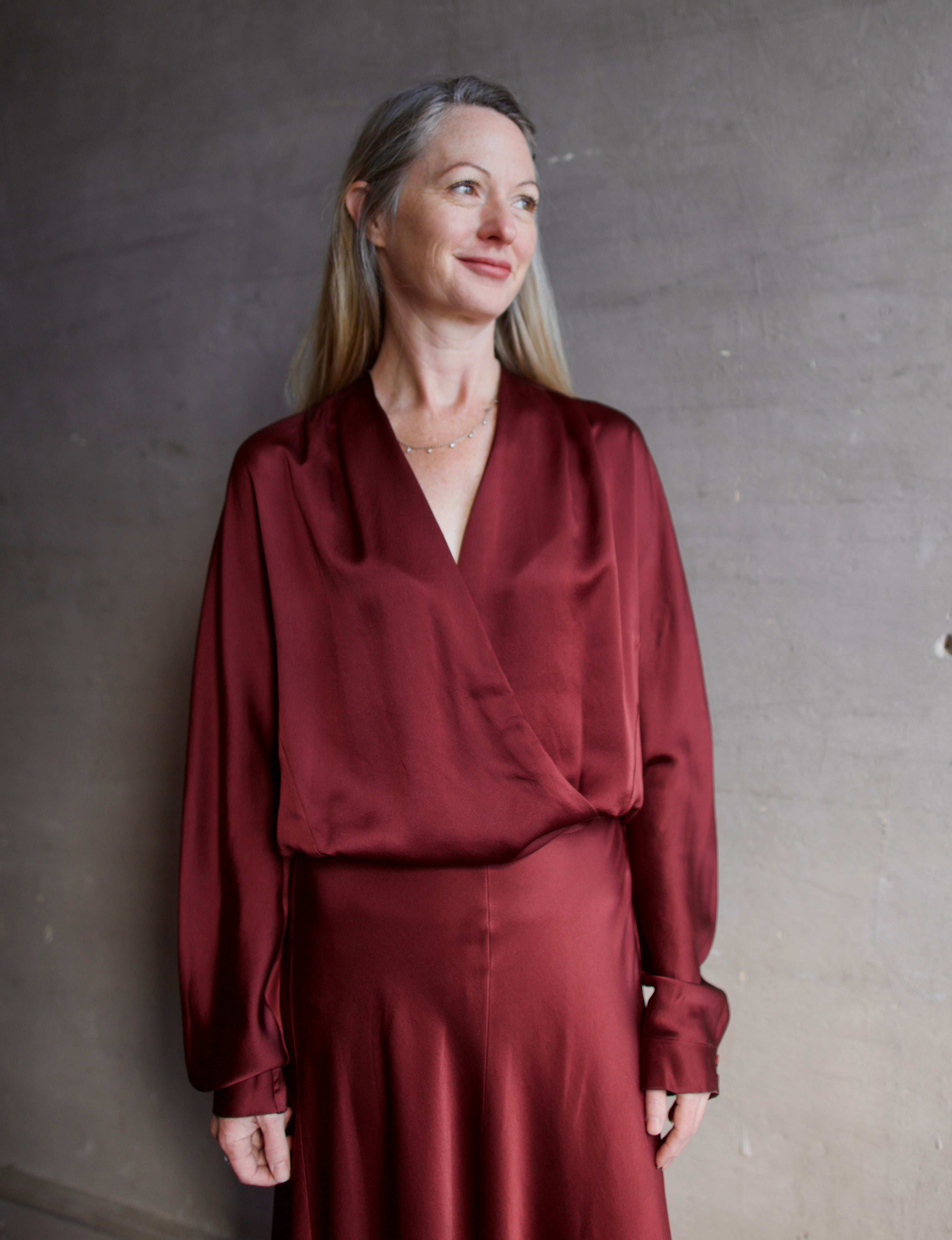 Image featuring a woman wearing the burgundy silk blouse by Forte Forte with wrap styling and an elastic waist.