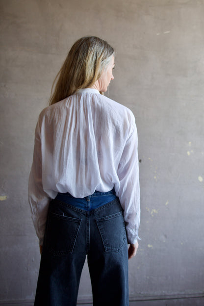 Image featuring a woman wearing the voile bohemian shirt by Forte Forte with a hook and eye closure and crystal embellishment at  the mandarin collar and sleeve button.