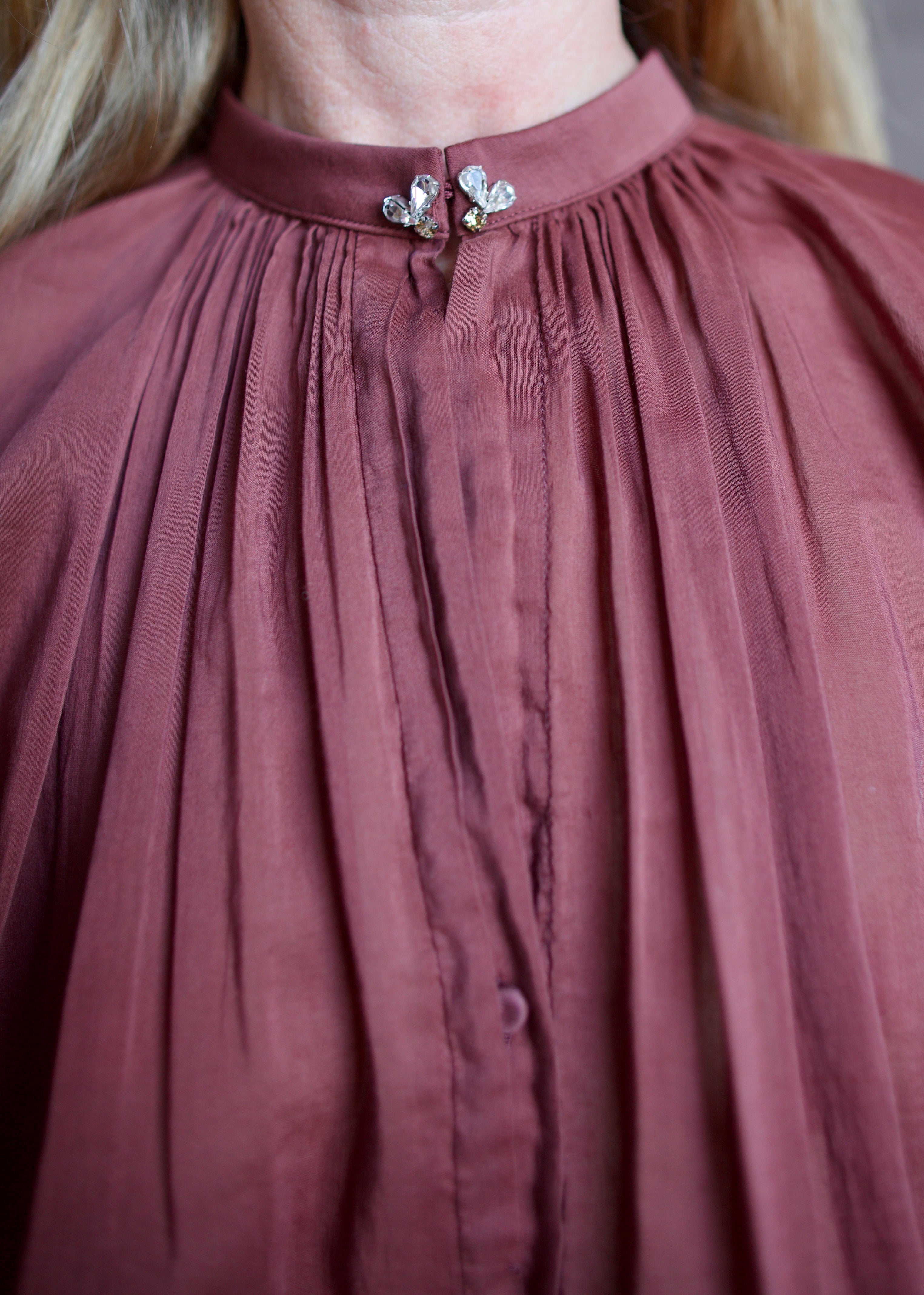 Image featuring a woman wearing the voile bohemian shirt by Forte Forte with a hook and eye closure and crystal embellishment at neckline and long sleeve button.