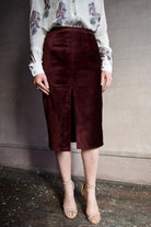 Image featuring a woman wearing the burgundy velvet pencil skirt by Forte Forte in a high rise, tailored fit with seam detailing and a high front slit.