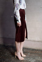 Image featuring a woman wearing the burgundy velvet pencil skirt by Forte Forte in a high rise, tailored fit with seam detailing and a high front slit.