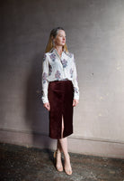 Image featuring a woman wearing the burgundy velvet pencil skirt by Forte Forte in a high rise, tailored fit with seam detailing and a high front slit.