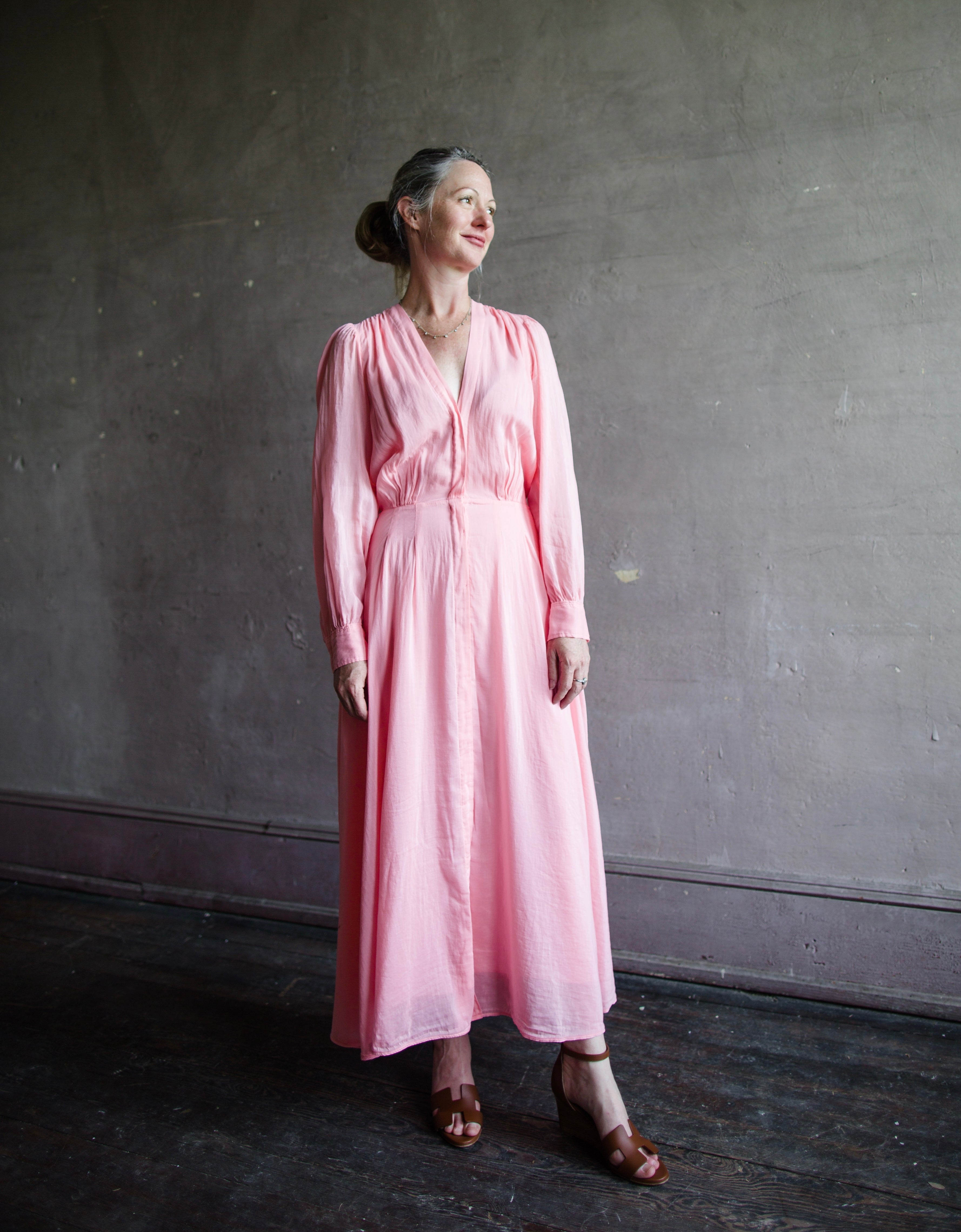 Image of a woman wearing the voile long sleeve dress by Forte Forte with a deep v neckline and tailored waist fabricated in pink cotton silk.