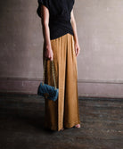 Image featuring a woman wearing the matte corduroy pants by Forte Forte with an elastic waist and flowy wide leg in caramel brown.