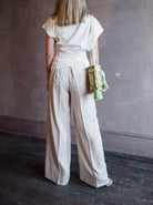 Image featuring a woman wearing the matte corduroy pants by Forte Forte with an elastic waist and flowy wide leg in ivory.