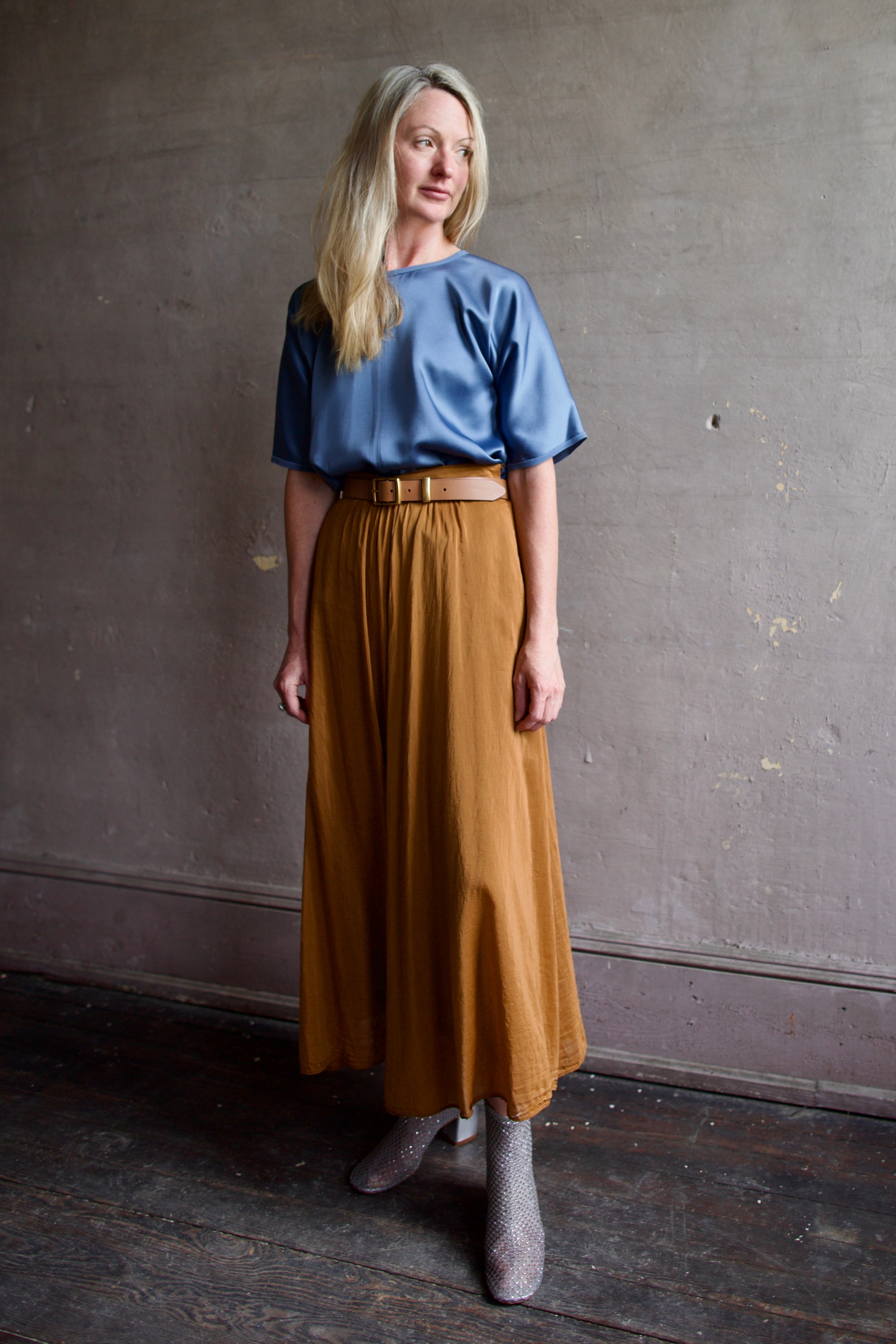 Senior model wearing luxury Italian fashion designer Forte Forte blue top, copper skirt and silver crystal boots