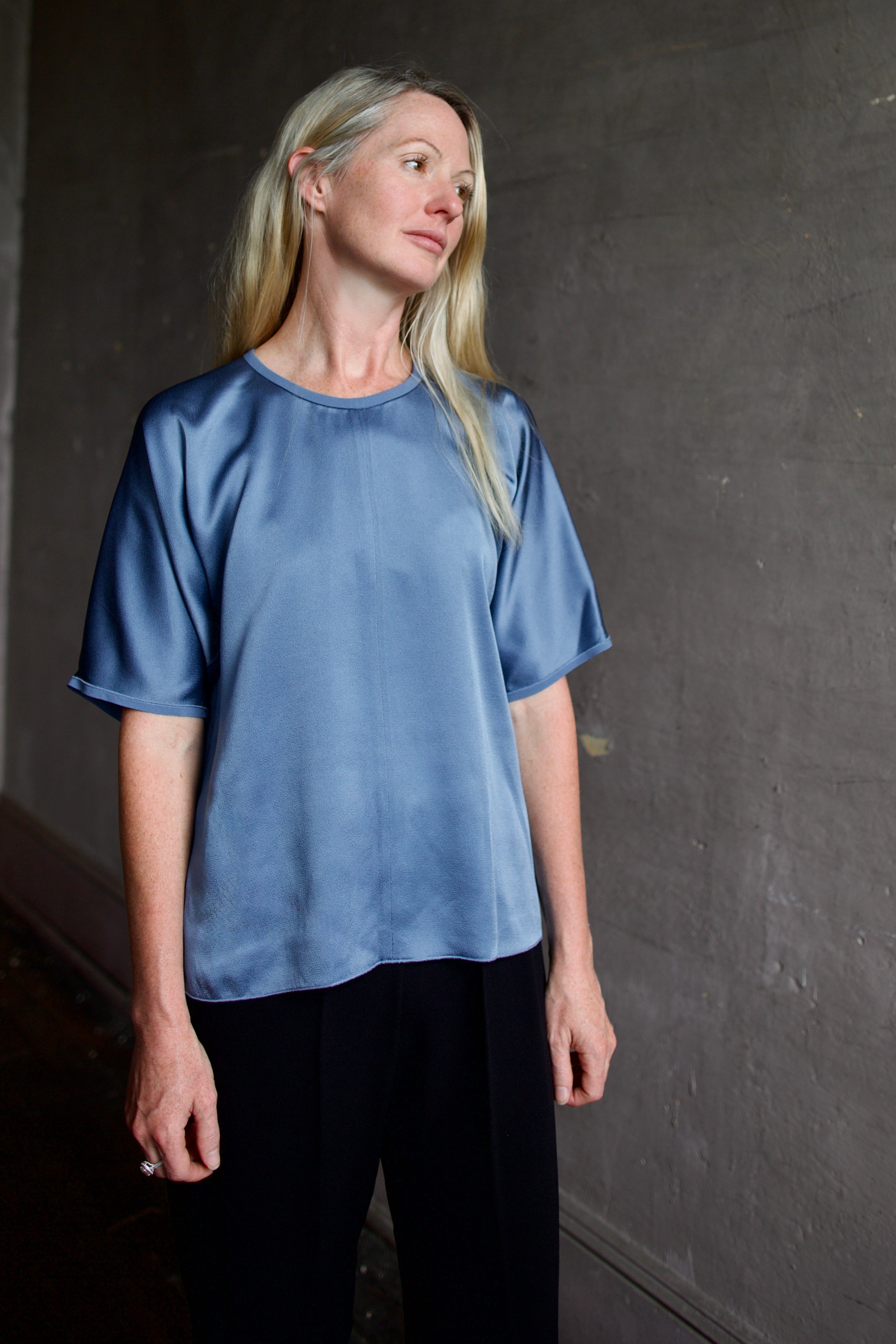 Senior model wearing luxury Italian fashion designer Forte Forte short sleeve blue top and black tuxedo stripe trousers