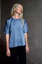 Senior model wearing luxury Italian fashion designer Forte Forte short sleeve blue top and black tuxedo stripe trousers