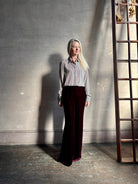Mature woman wearing dark burgundy velvet Italian made flared trousers from Forte Forte