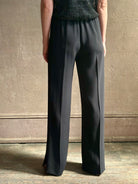Mature model wearing luxury Italian designer Forte Forte black wide-leg pull on pants with satin tuxedo side stripe and bottom slit