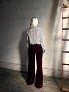 Back image of mature woman wearing Forte_Forte Plain Velvet Flare Pants in Burgundy with flexible elastic waistband at back