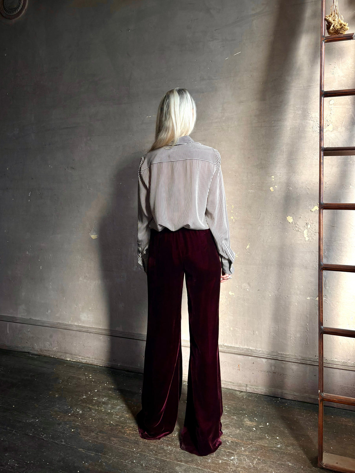 Back image of mature woman wearing Forte_Forte Plain Velvet Flare Pants in Burgundy with flexible elastic waistband at back