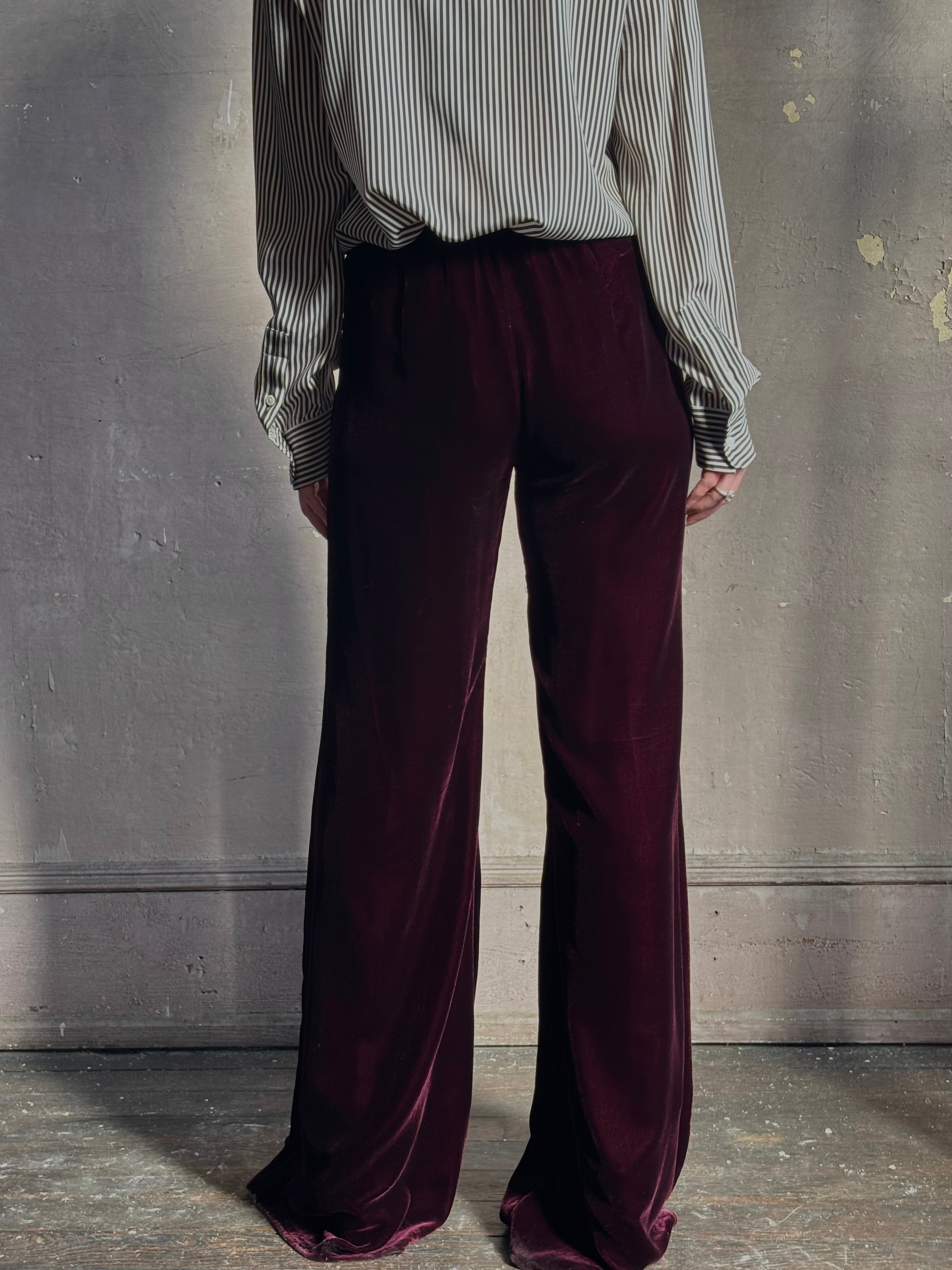 Back image of mature woman wearing Forte_Forte Plain Velvet Flare Pants in Burgundy with flexible elastic waistband at back