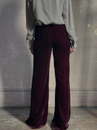 Back image of mature woman wearing Forte_Forte Plain Velvet Flare Pants in Burgundy with flexible elastic waistband at back