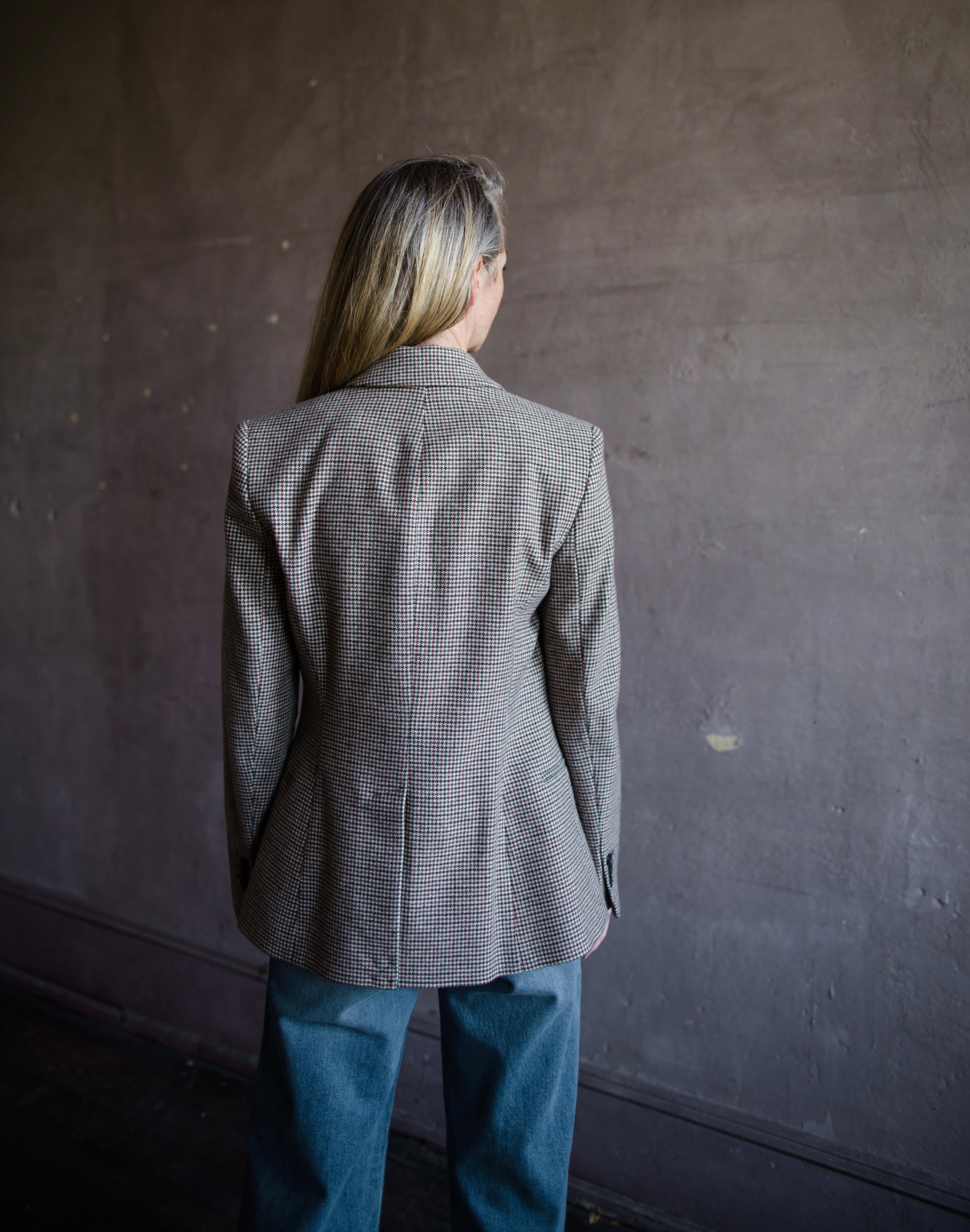 Image featuring a woman wearing the Frame Femme Blazer in hounds tooth wool with two-button long sleeve jacket, notch lapels, chest and side pockets.