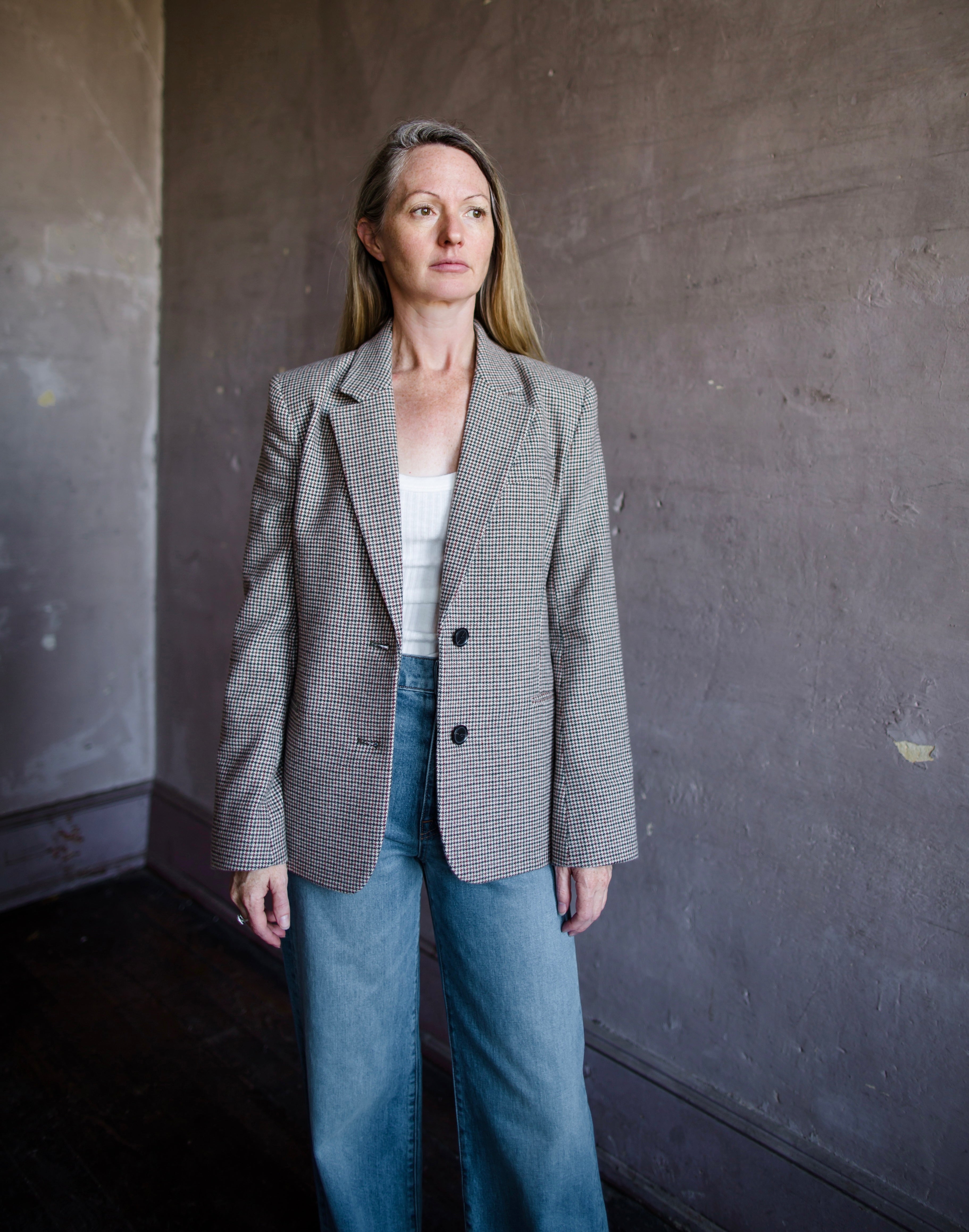 Image featuring a woman wearing the Frame Femme Blazer in hounds tooth wool with two-button long sleeve jacket, notch lapels, chest and side pockets.