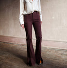 Image featuring a woman wearing the Frame Le High Flare sophisticated brown trousers with front seam slits.